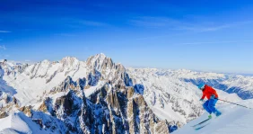 A skier heads down the mountain under blue skies in Gressoney