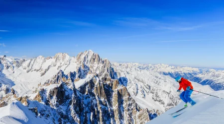 A skier heads down the mountain under blue skies